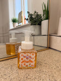 Hand soap bottle with pump on a bathroom counter, mirror in the background